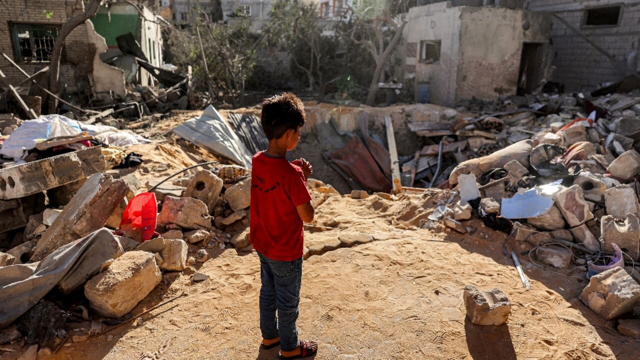 A boy stands before a crater where a building hit by Israeli bombardment in Rafah once stood A boy stands before a crater where a building hit by Israeli bombardment in Rafah once stood