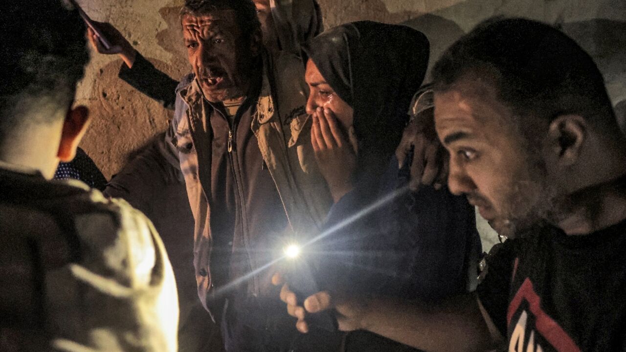 Palestinians gather around a wounded relative as rescuers search for people under the rubble of a Rafah home