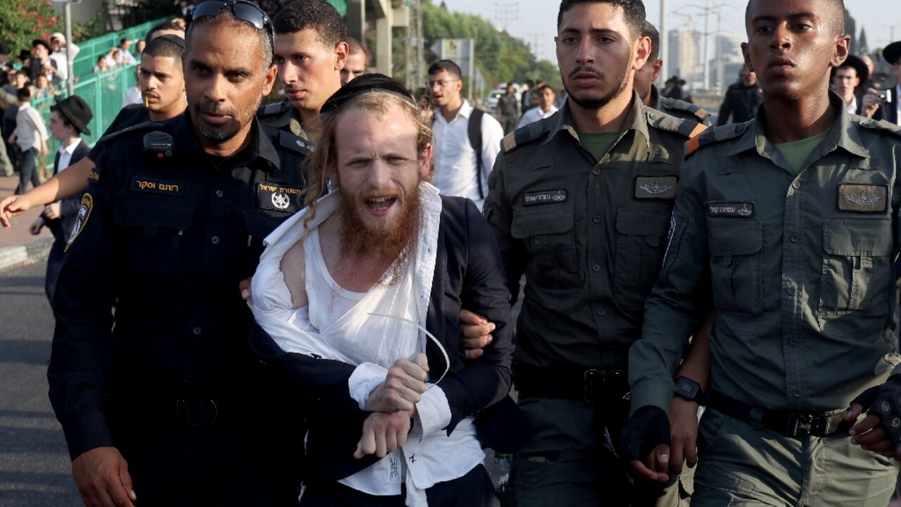 Israeli police detain a man as they they try to disperse ultra-Orthodox Jews blocking a highway during a protest against possible changes regarding the laws on the military draft