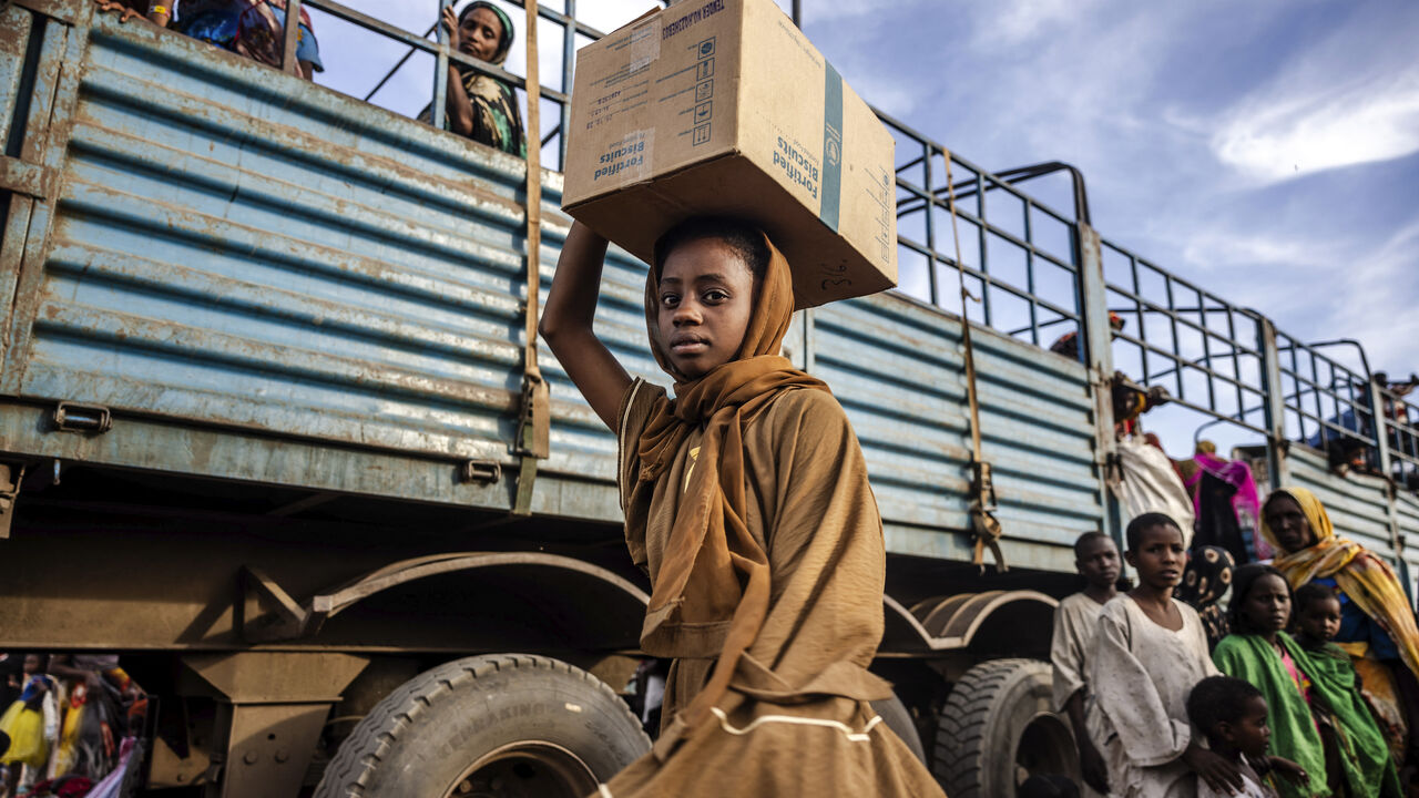 A Sudanese girl who have fled from the war in Sudan with her family carry a box with some of her belongings after arriving at a Transit Centre for refugees in Renk, on February 13, 2024.More than 550,000 people have now fled from the war in Sudan to South Sudan since the conflict exploded in April 2023, according to the United Nations. South Sudan, that has itself recently come out of decades of war, was facing a dire humanitarian situation before the war in Sudan erupted and it is feared to not have the re