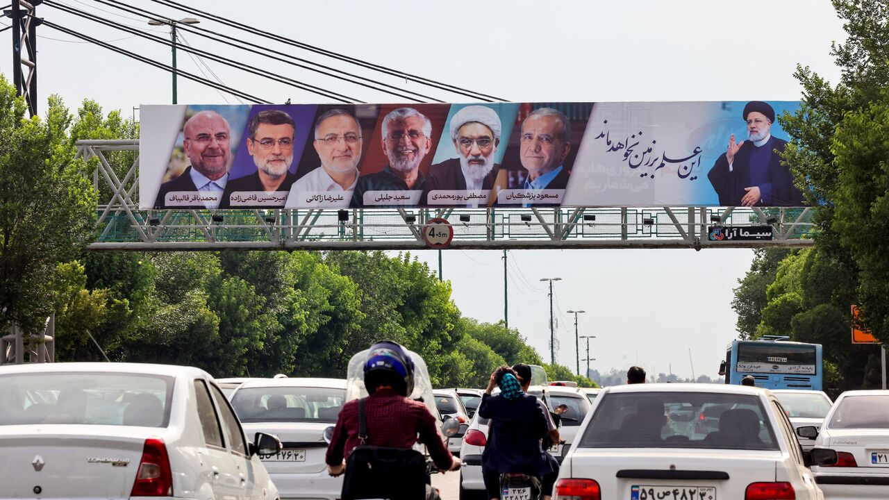 Vehicles move past a billboard displaying the faces of the six candidates running in the upcoming Iranian presidential election in the Iranian capital Tehran on June 16, 2024.