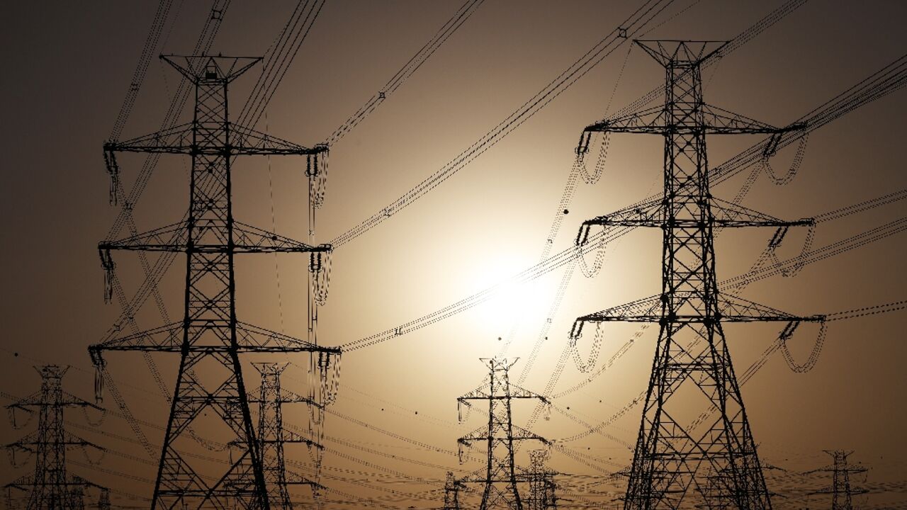 The sun sets behind overhead power lines in Kuwait City -- the electricity ministry said power plants were unable to meet increased demand