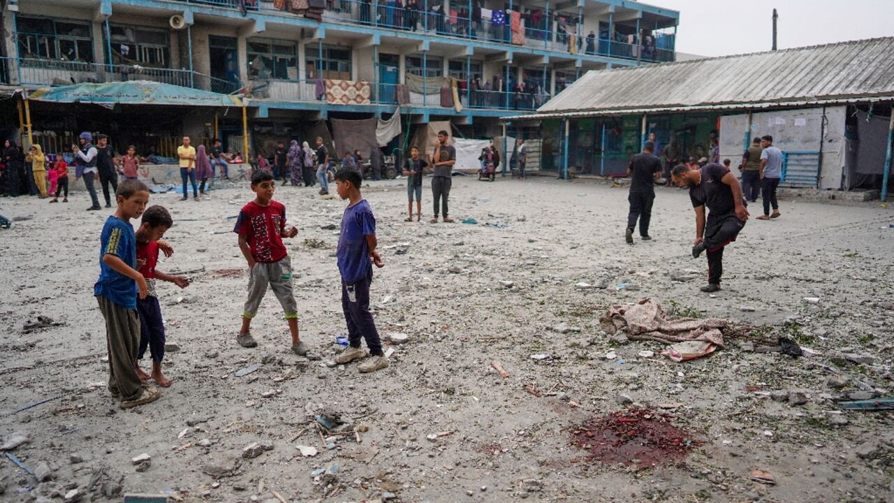 Palestinian boys stand near blood stains at a UN school housing displaced people that was hit during Israeli bombardment in Nuseirat in the central Gaza Strip