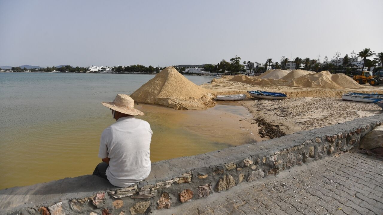 A man looks on as a digger spreads sand on a beach in the tourist town of Hammamet as authorities fight to protect the coast from rising sea levels and erosion A man looks on as a digger spreads sand on a beach in the tourist town of Hammamet as authorities fight to protect the coast from rising sea levels and erosion