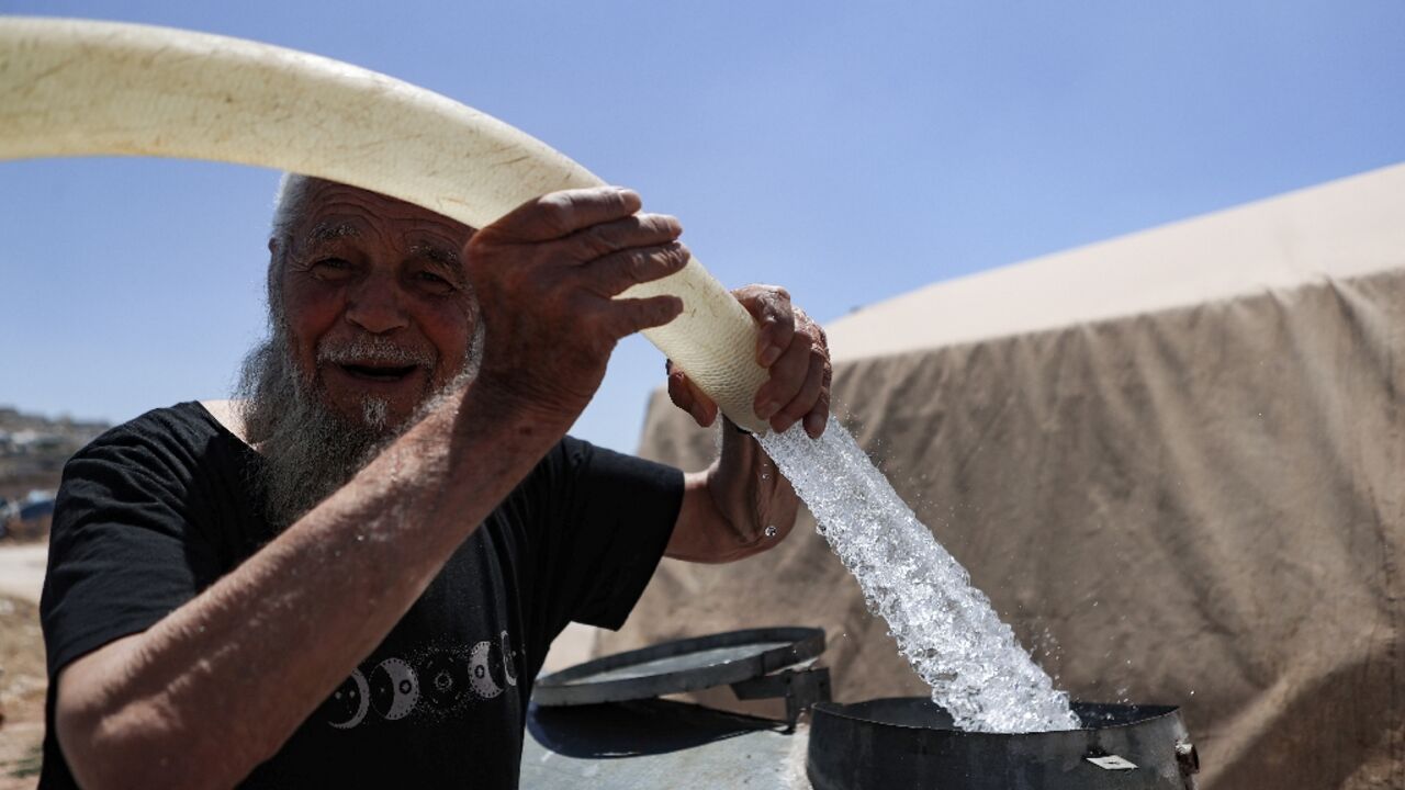 A man fills barrels with water at a camp for internally displaced people in northern Syria A man fills barrels with water at a camp for internally displaced people in northern Syria