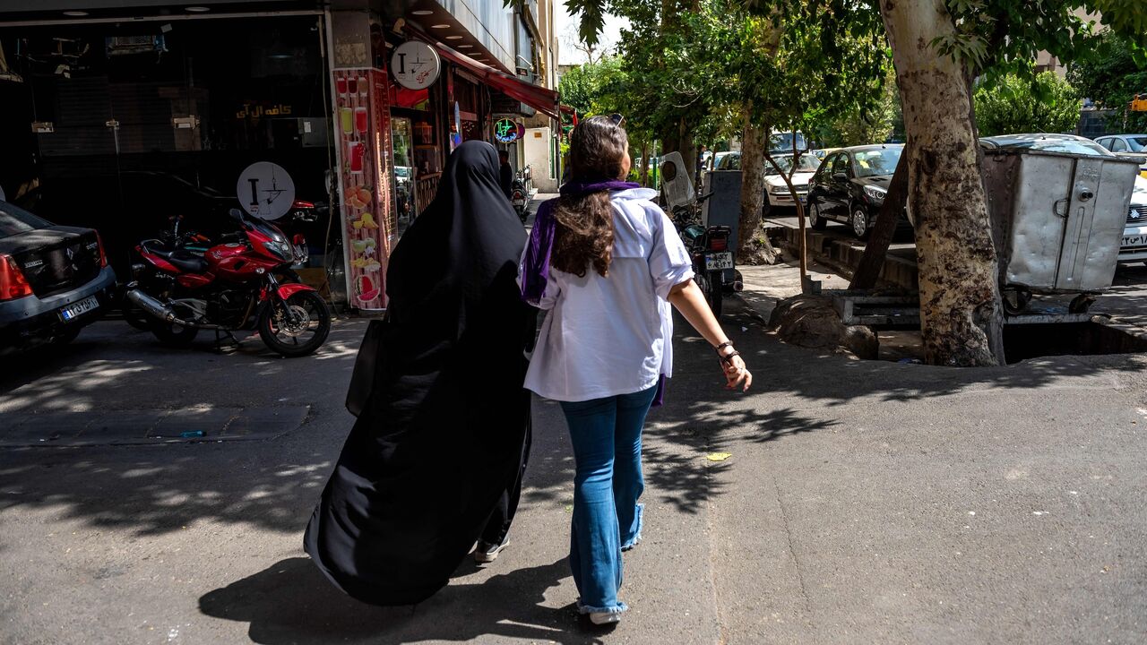 Two Iranian women are walking in the street of Tehran with optional covering.