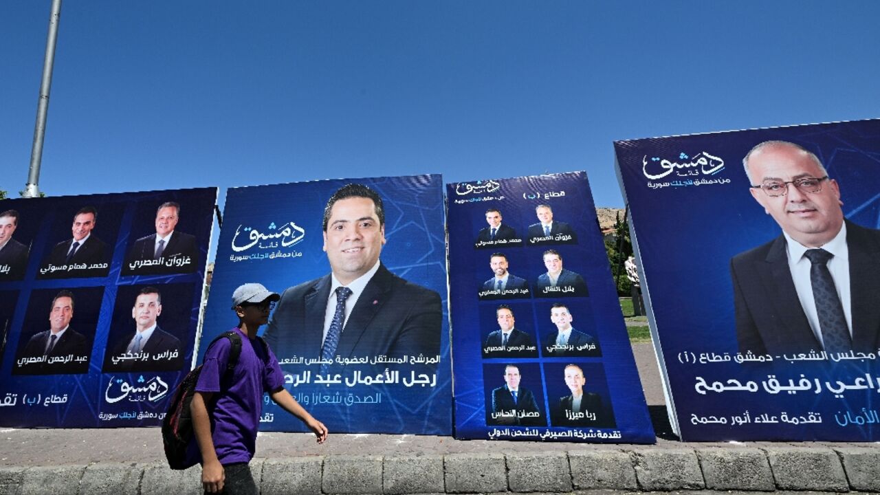 A young man walks past electoral campaign posters in Damascus a day ahead of parliamentary elections in government-held areas of Syria