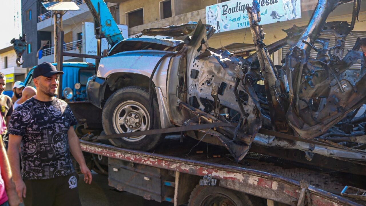 Lebanese remove the wreckage of the car in which a Hamas-allied commander was killed in an Israeli air strike