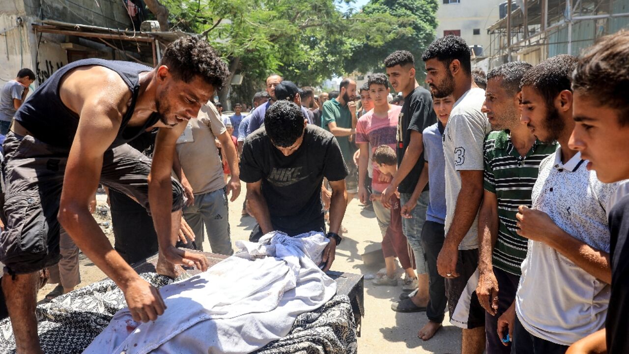 A body is wrapped in a white sheet after Israeli bombardment at the al-Bureij refugee camp in the central Gaza Strip on July 9, 2024