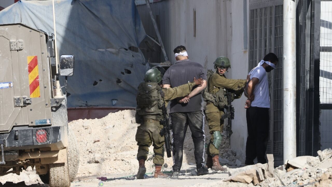 Israeli soldiers arrest Palestinians during a raid in the Nur Shams refugee camp in the occupied West Bank