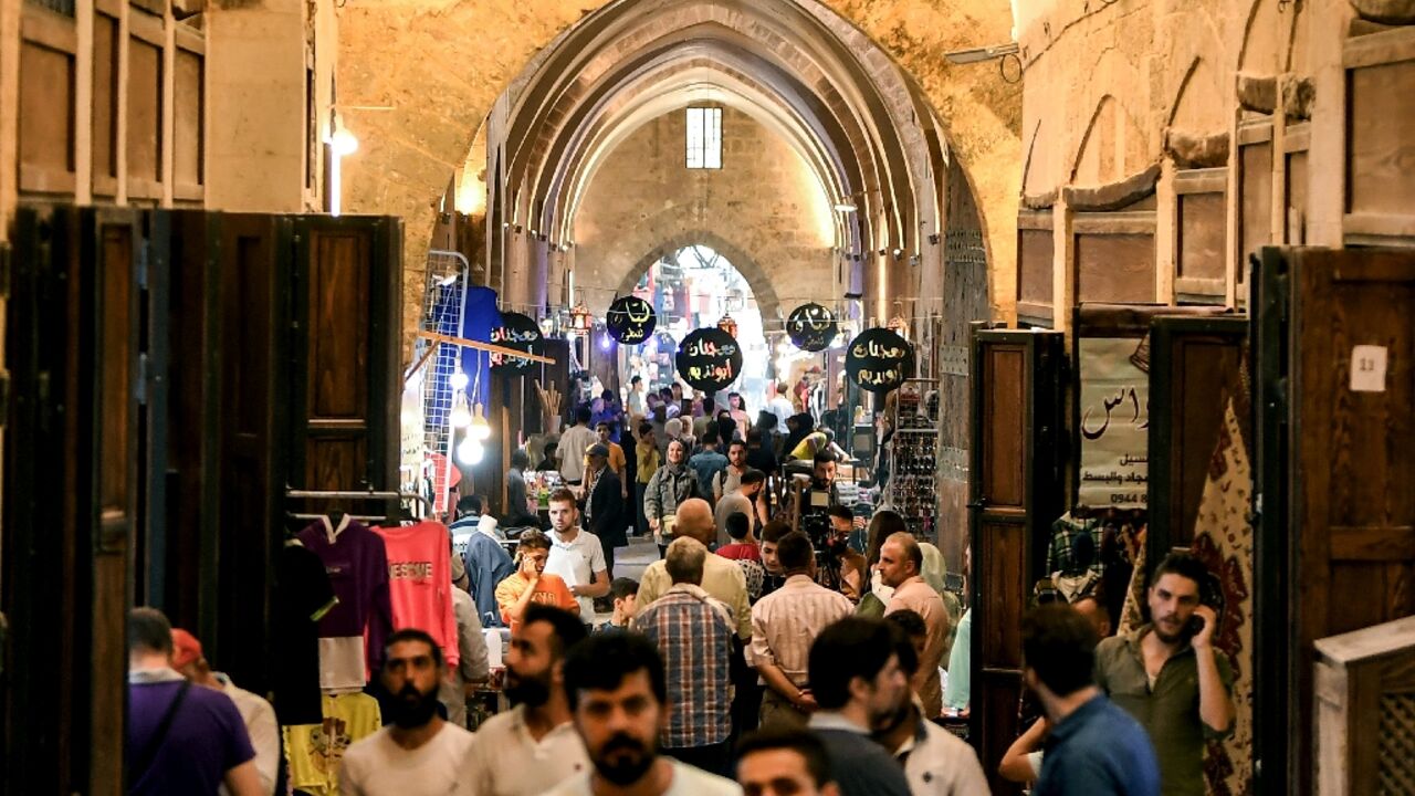 People walk along an alley during the reopening of restored bazaars that were damaged during the Syrian conflict in the northern city of Aleppo