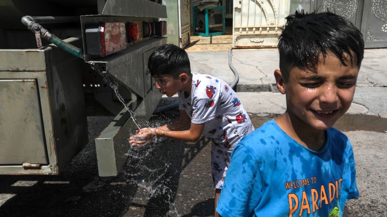 Boys cool off with water from a mobile tanker as summer temperatures soar in Iraq's northern autonomous Kurdish region