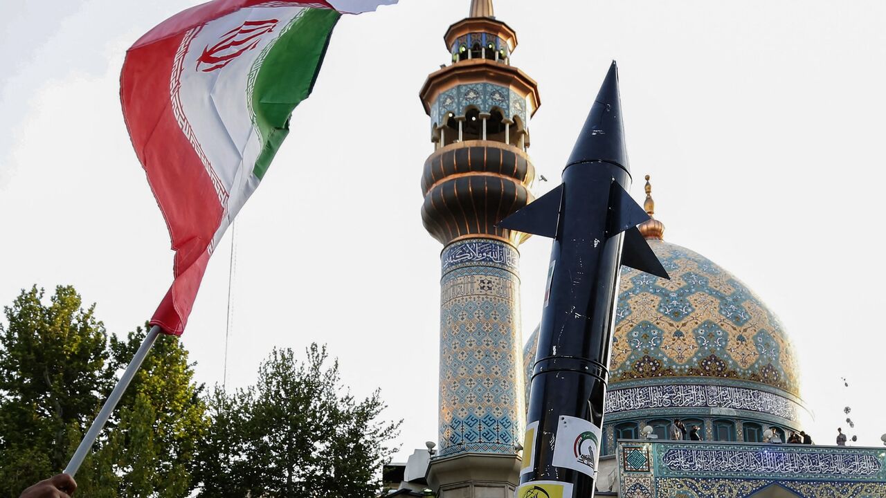 Iranians lift up a flag and the mock up of a missile during a celebration following Iran's missiles and drones attack on Israel, on April 15 2024, at Palestine square in central Tehran.