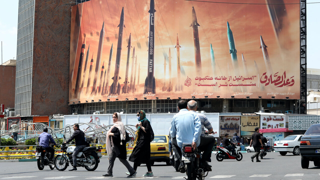 Motorists drive their vehicles past a billboard depicting Iranian missiles in Tehran on April 20, 2024, a day after Iran's state media reported explosions in the central province of Isfahan.
