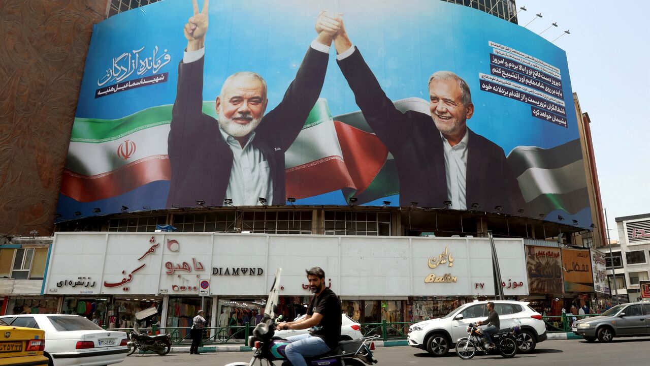 Iranians drive next to a billboard of Iranian President Masoud Pezeshkian (R) and late Hamas leader Ismail Haniyeh at the Valise square in Tehran on Aug. 1, 2024. 