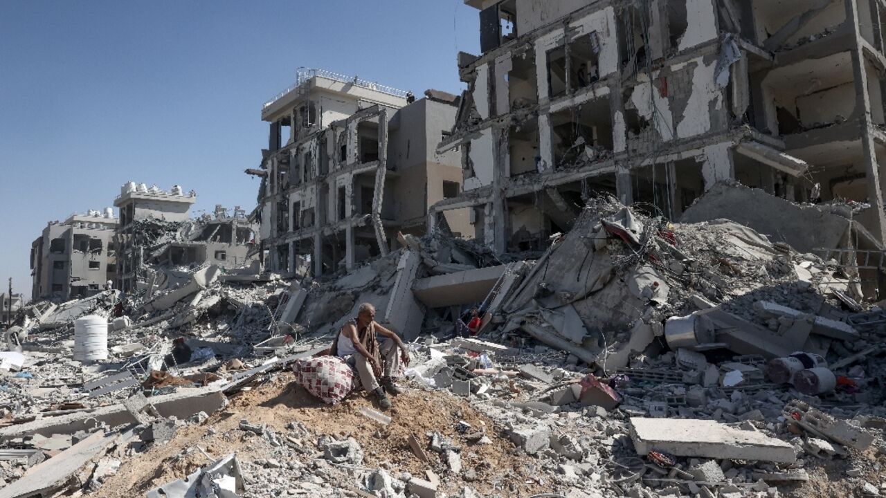 A Palestinian man who returned to Deir al-Balah in the central Gaza Strip to check on his home sits atop items salvaged amid the devastation