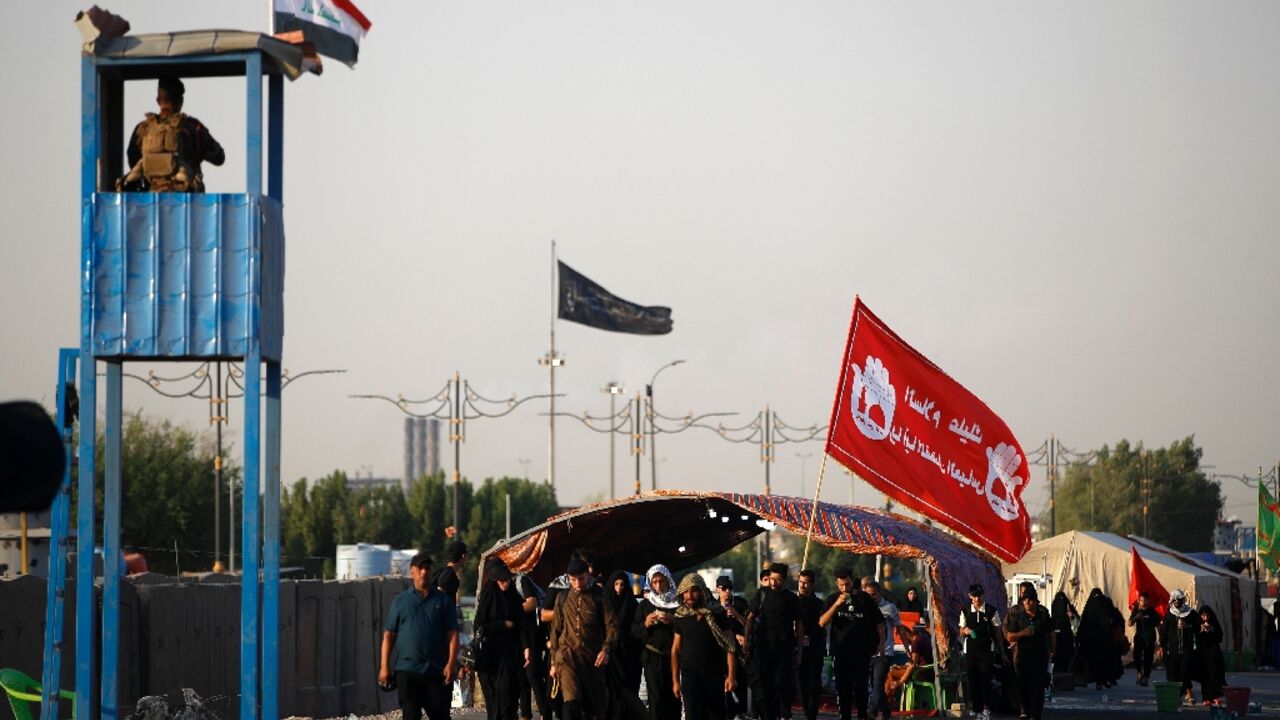 A member of the Iraqi security forces stands guard as Shiite Muslim pilgrims walk near Baghdad on their way to Karbala ahead of Arbaeen commemorations 