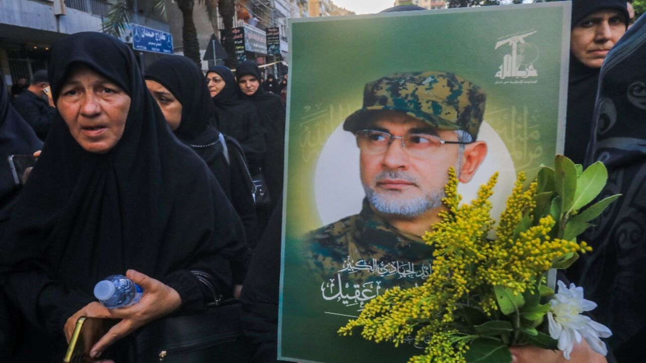 Black-clad mourners file past, one bearing a picture of killed Radwan Force chief Ibrahim Aqil Black-clad mourners file past, one bearing a picture of killed Radwan Force chief Ibrahim Aqil