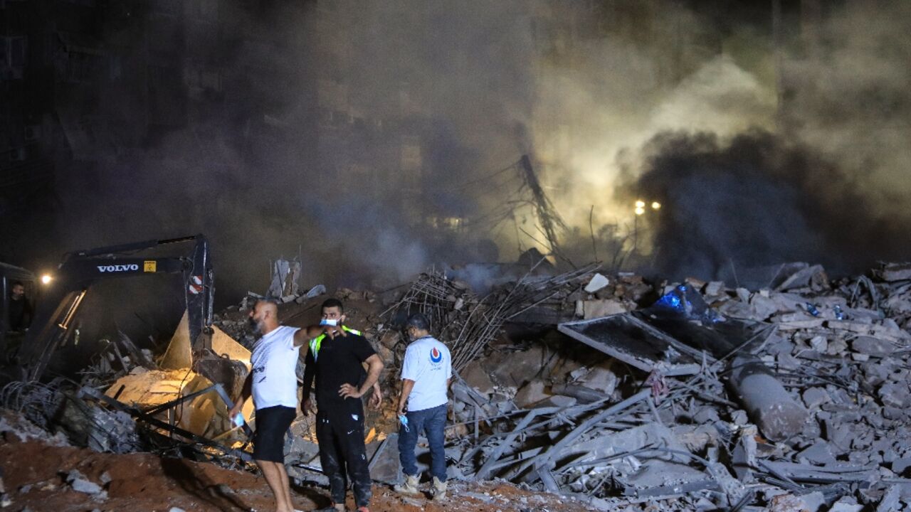 Rescuers inspect the rubble of a building destroyed in the Israel strike on Beirut's southern suburbs