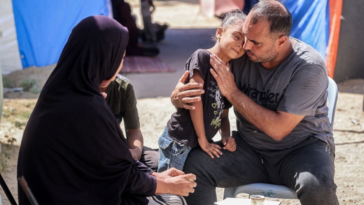 Maher Zino, 39, sits with his wife and children for coffee outside their tent at a makeshift camp in the central Gaza Strip Maher Zino, 39, sits with his wife and children for coffee outside their tent at a makeshift camp in the central Gaza Strip