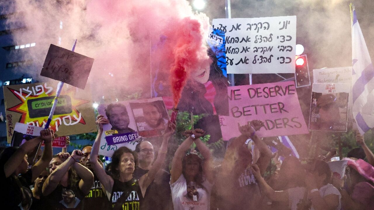 Demonstrators hold placards and set off smoke bombs during an anti-government rally in Israel's Tel Aviv