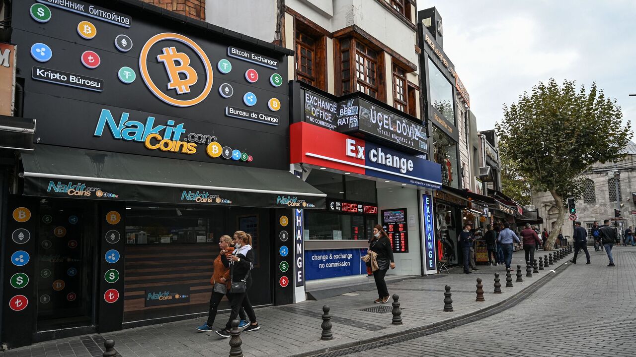 People pass by a cryptocurrency exchange branch near the Grand Bazaar in Istanbul on Oct. 20, 2021, a day after Bitcoin took another step closer to mainstream investing with the launch of a new security on Wall Street tied to futures of the cryptocurrency.