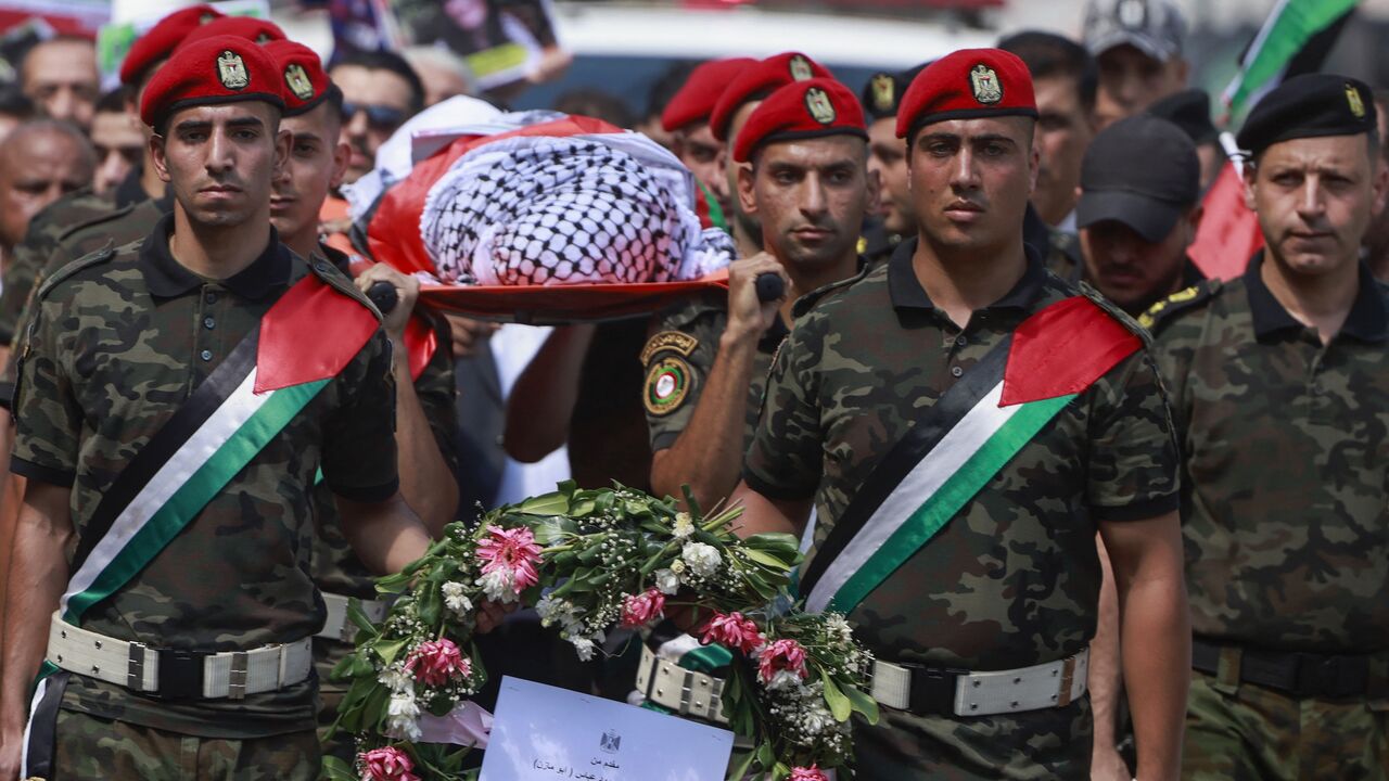 Members of Palestinian security forces carry the body of slain Turkish-American International Solidarity Movement activist Aysenur Ezgi Eygi.