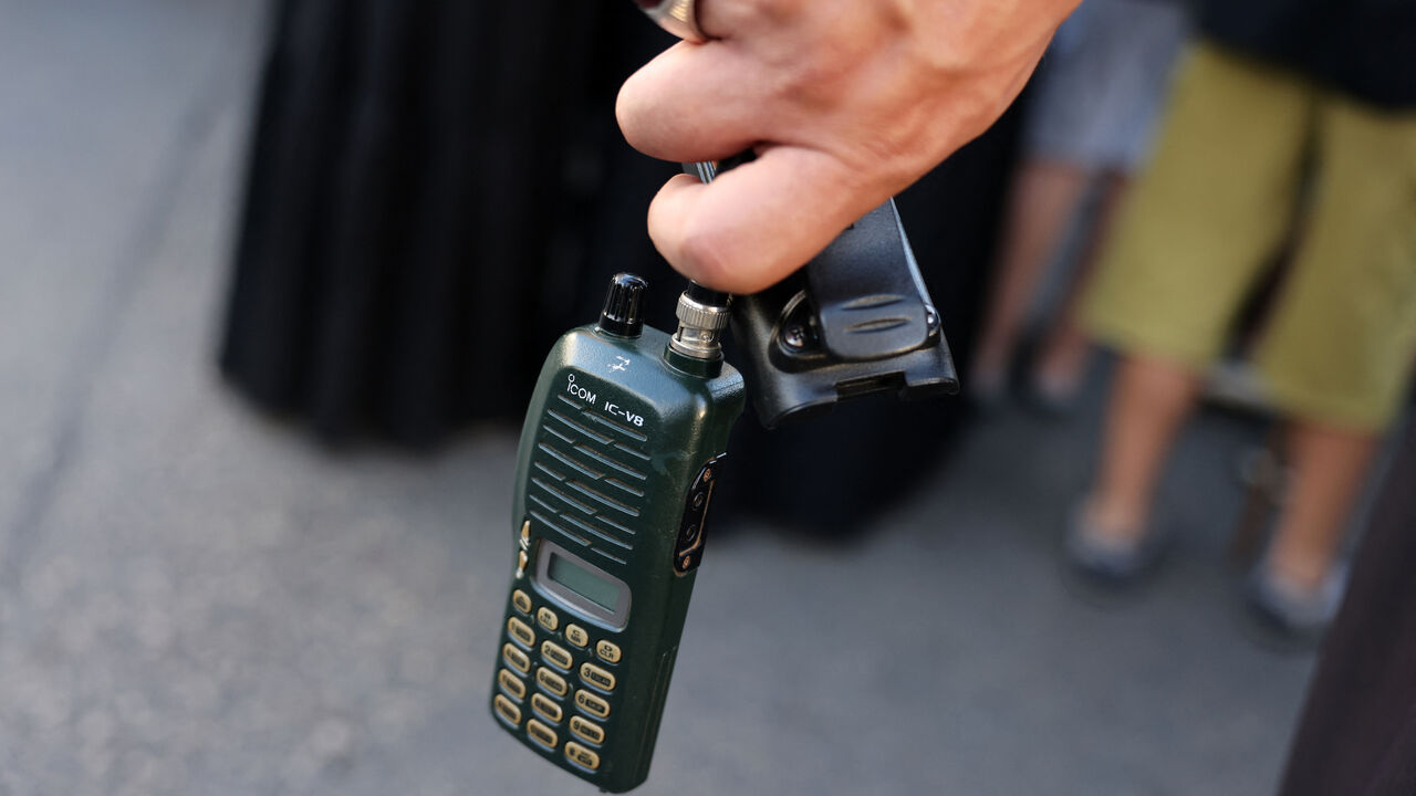 A man holds an Icom walkie talkie device after he removed the battery during the funeral of persons killed when hundreds of paging devices exploded in a deadly wave across Lebanon the previous day, in Beirut's southern suburbs on Sept. 18, 2024. 