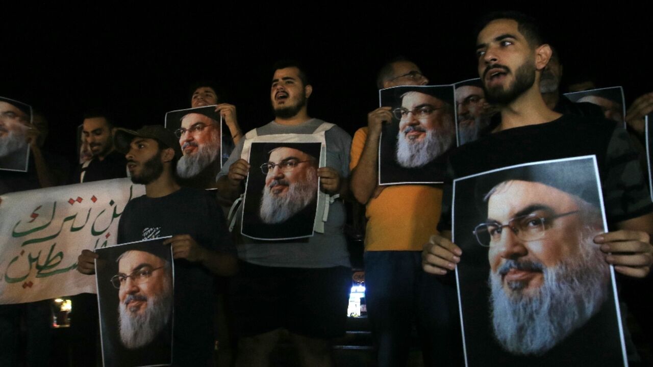 Demonstrators hold pictures of slain Hezbollah leader Hassan Nasrallah during a protest vigil in the southern Lebanese city of Sidon