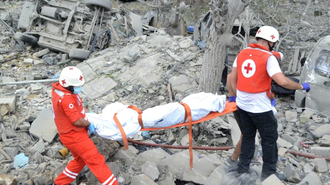 Paramedics carry a body from the rubble at the site of the Israeli airstrike in Aito Paramedics carry a body from the rubble at the site of the Israeli airstrike in Aito