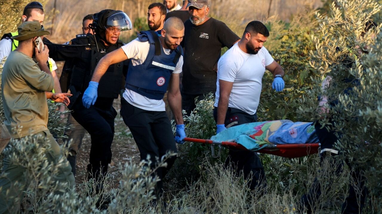 First responders carry the shrouded body of a woman killed when a rocket fired from Lebanon hit an area near Kiryat Ata in northern Israel's Haifa district