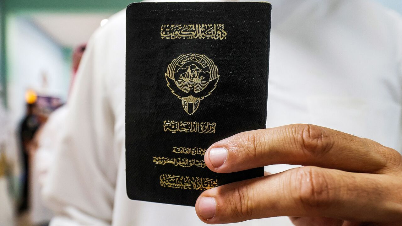 A voter holds his proof of Kuwaiti citizenship upon arriving at a polling station during parliamentary elections in Kuwait City on June 6, 2023. 