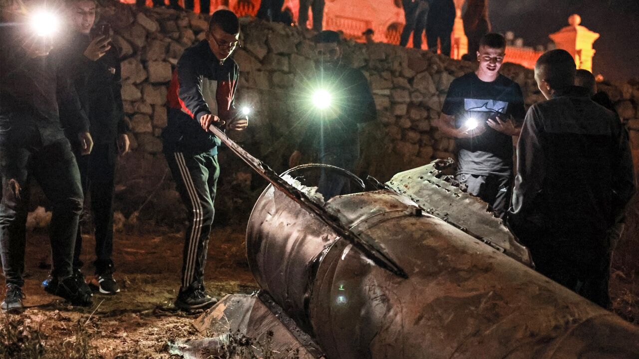 Palestinian youths inspect a fallen projectile after Iran launched a barrage of missiles at Israel in response to the killings of Lebanese Hezbollah leader Nasrallah.