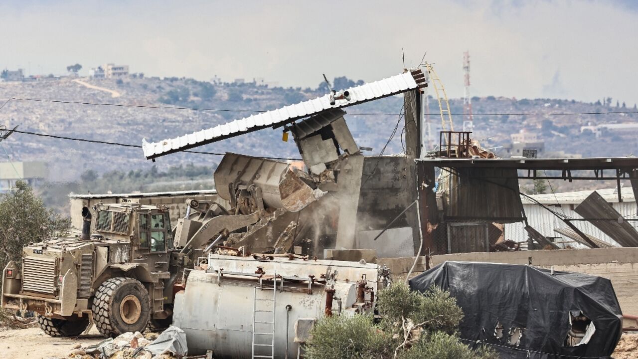 An Israeli military bulldozer demolishes buildings in Qabatiyah