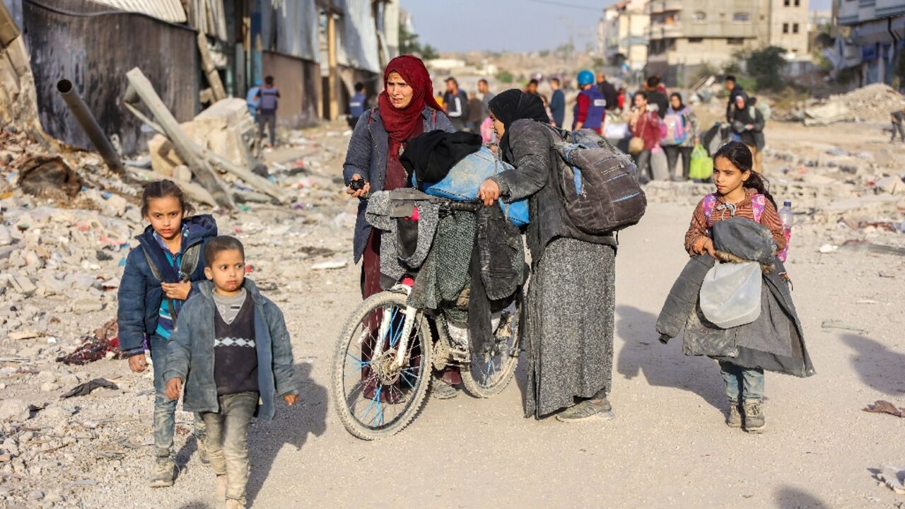 Displaced Palestinians fleeing Beit Lahia in northern Gaza walk on the main Salah al-Din Road