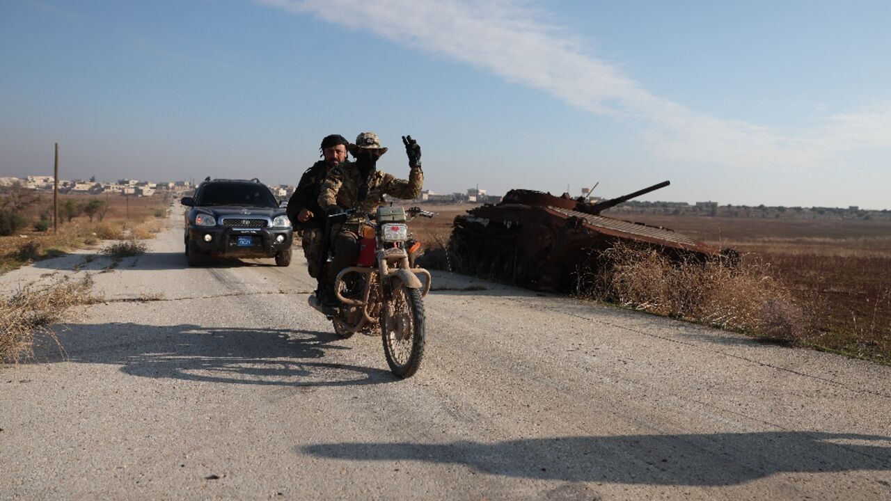 Fighters pass a damaged Syrian Army tank in Miznaz, Syria, which was taken over by jihadists and their Turkish-backed allies in battles with government forces in Aleppo province Fighters pass a damaged Syrian Army tank in Miznaz, Syria, which was taken over by jihadists and their Turkish-backed allies in battles with government forces in Aleppo province