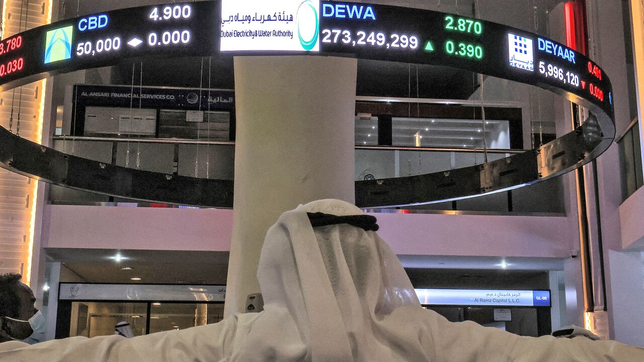 A man watches stock movements on a display at the Dubai Financial Market stock exchange in the Gulf emirate on April 12, 2022. 