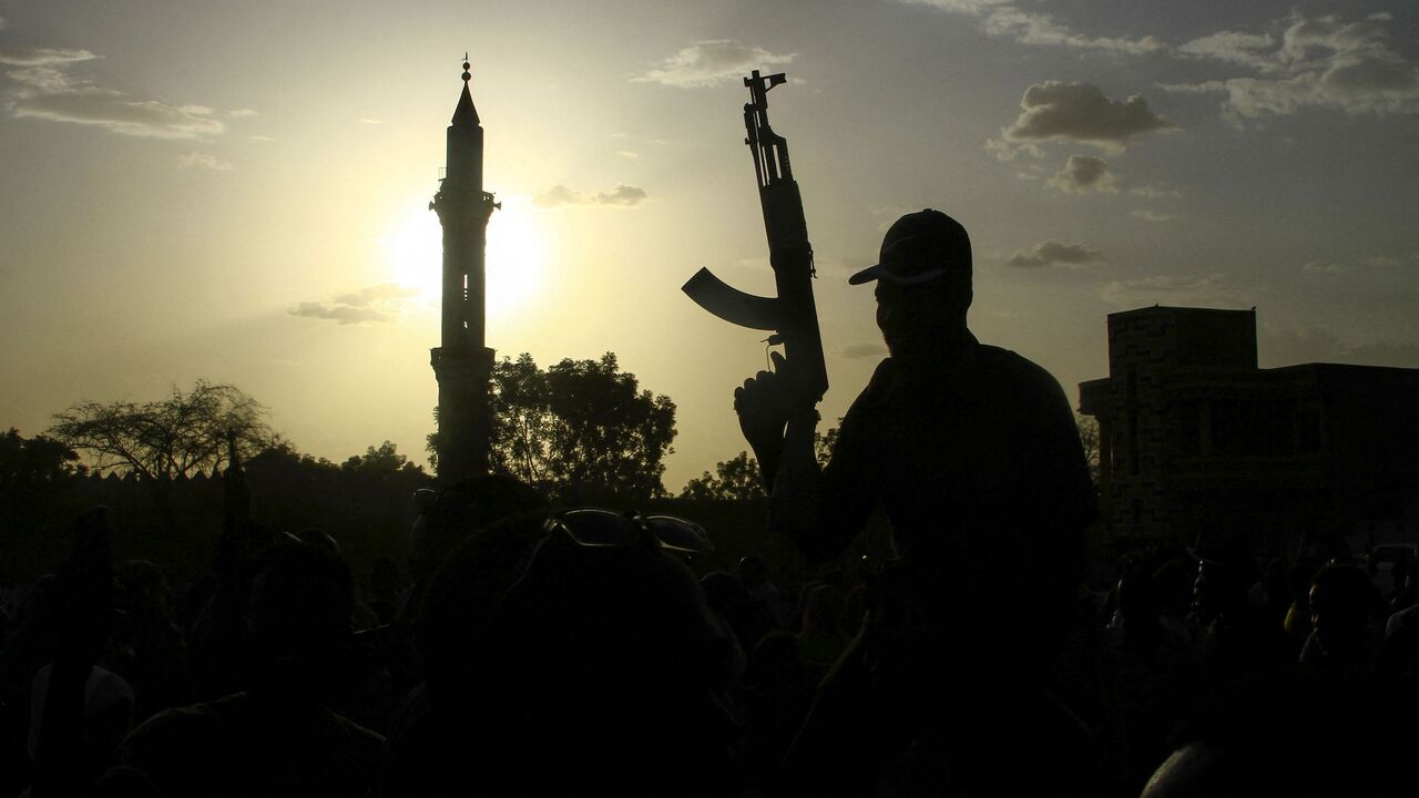 A fighter loyal to Sudan's army, chief Abdel Fattah al-Burhan, holds up a weapon against the backdrop of a mosque, during a graduation ceremony in the southeastern Gedaref state on May 27, 2024. 