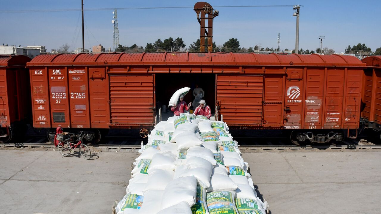 Afghan workers carry flour sacks off a freight train upon its arrival from Uzbekistan, at the border station in Hairatan, Balkh Province, March 5, 2024.