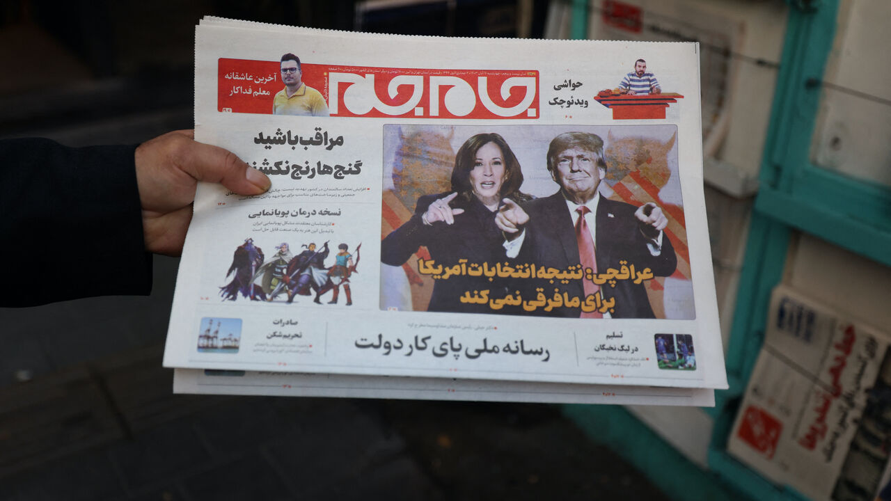 An Iranian holds a local newspapers with frontpage news on the US presidential vote outside a kiost in Tehran on Nov. 6, 2024.