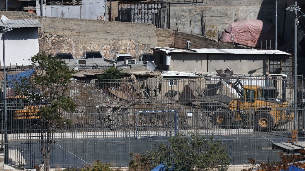 An excavator demolishes a home belonging to the Al-Ruwaidi family in Al-Bustan