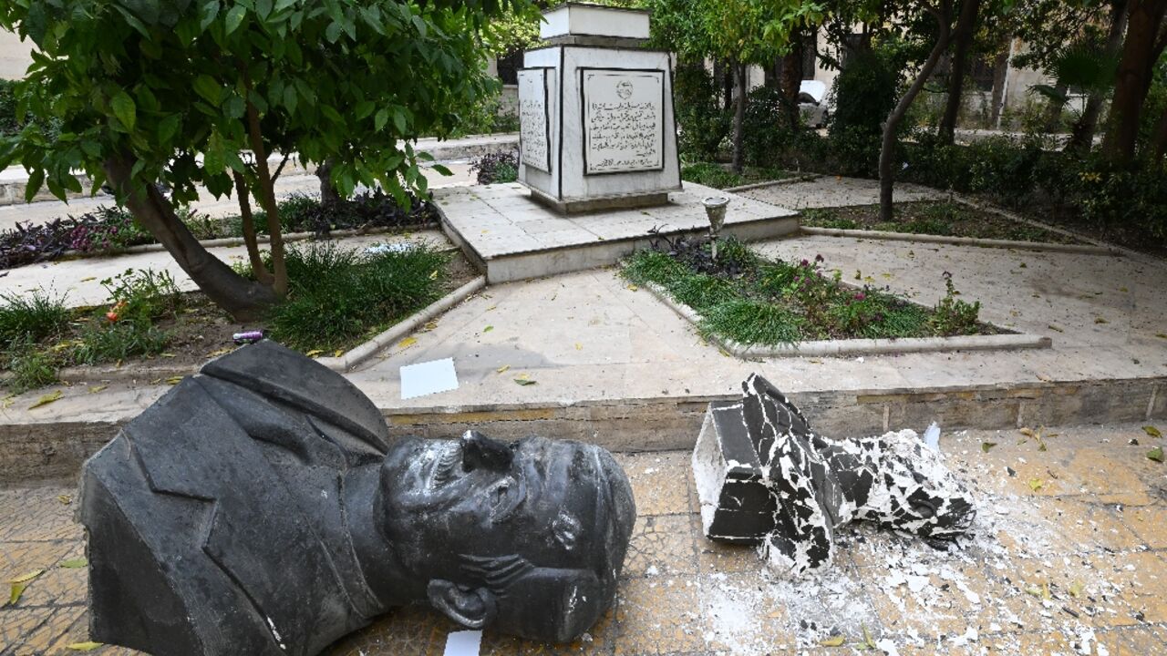 A broken statue of late Syrian president Hafez al-Assad lies outside the Baath party offices in Damascus