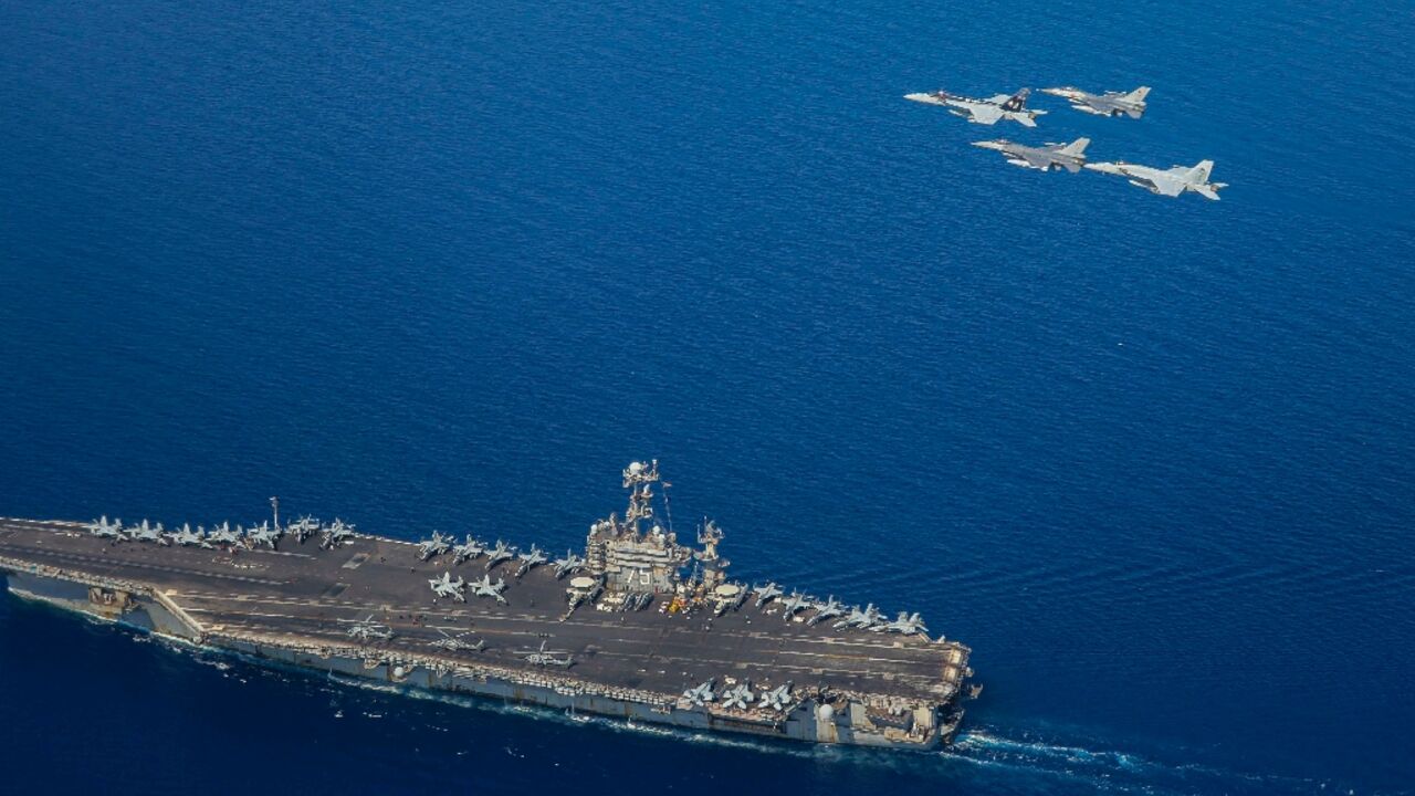 A handout file picture from the US Navy showing the USS Harry S Truman with F/A-18 and F-16 jets flying overhead