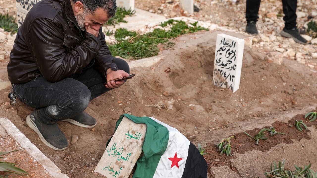 A mourner kneels by the graveside of award-winning Syrian photographer Anas Alkharboutli following his funeral in the rebel-held northwestern city of Idlib.