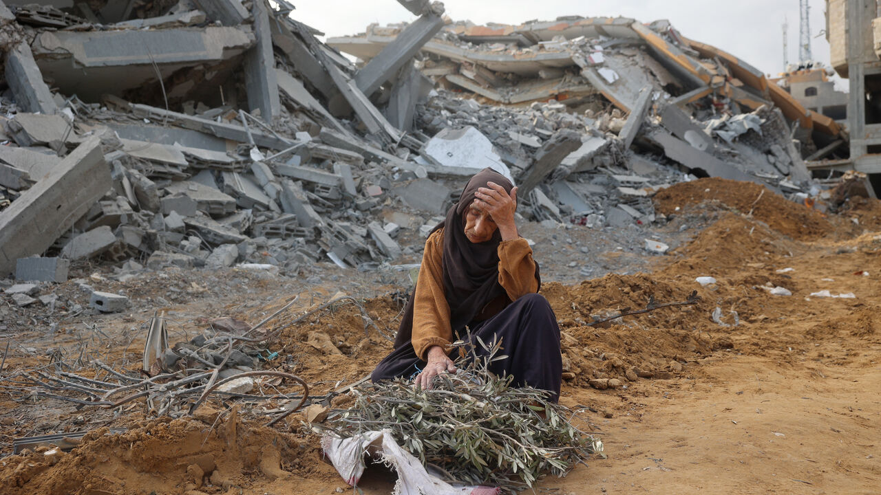 TOPSHOT - A elderly woman sits in front of a destroyed building to take a rest as she collects tree branches to light a fire in Nuseirat in the central Gaza Strip after Israeli shelling of the camp stopped on November 29, 2024, amid the ongoing war in the Palestinian territory between Israel and Hamas. (Photo by Eyad BABA / AFP) (Photo by EYAD BABA/AFP via Getty Images)