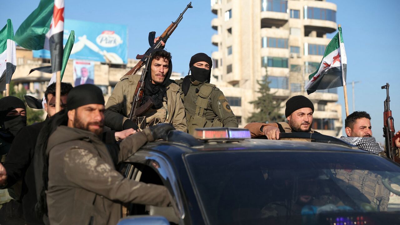 Anti-government fighters brandish their guns as they ride a vehicle in Syria's northern city of Aleppo on Nov. 30, 2024. 