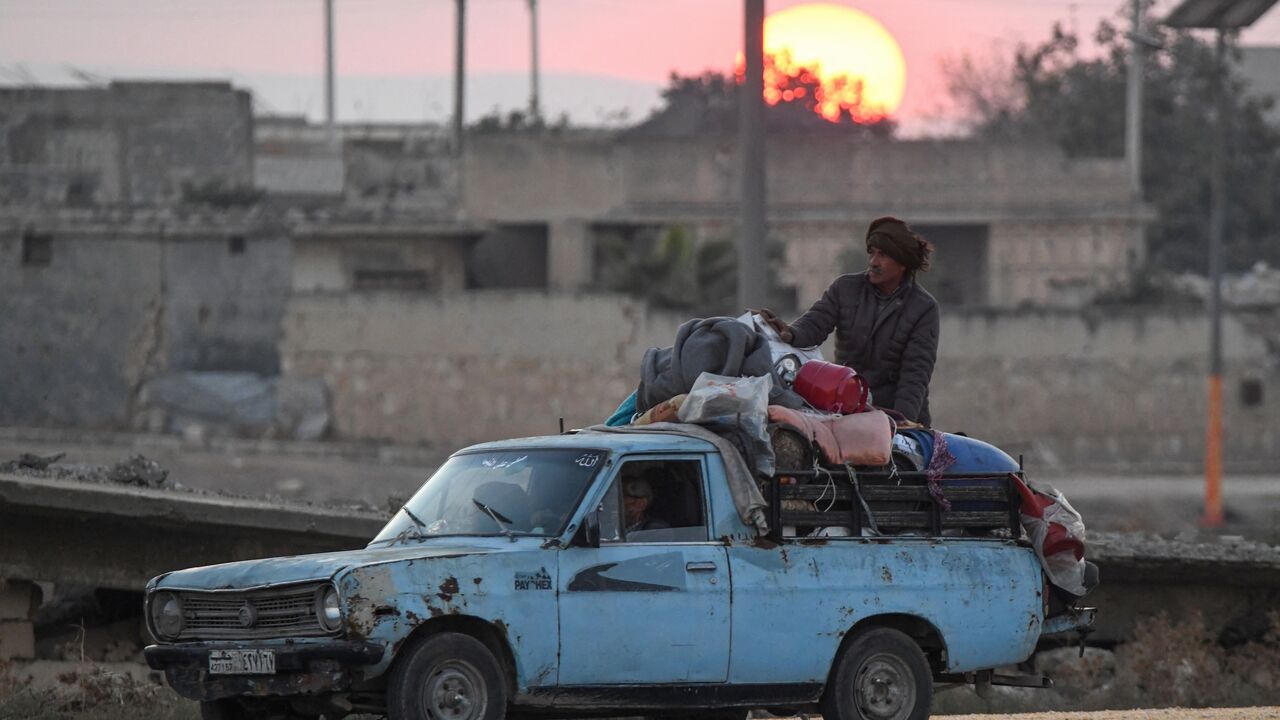 Displaced Syrian Kurds drive a vehicle loaded with belongings on the Aleppo-Raqqa highway.