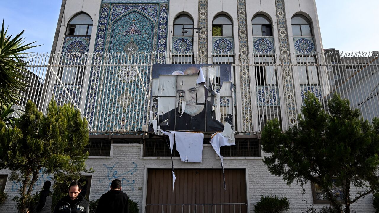 Syrian men stand outside the building of the Iranian Embassy.