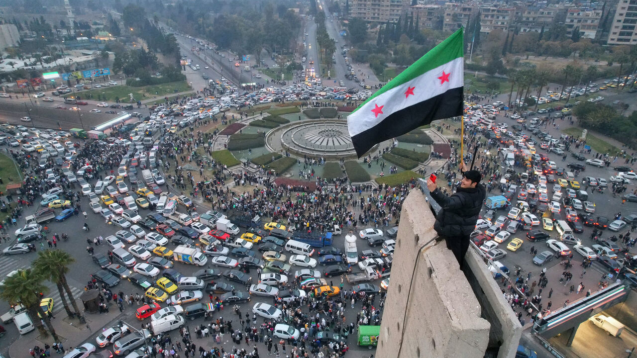An aerial view shows a Syrian man waving the independence-era Syrian flag at Damascus' central Umayyad Square on Dec. 11, 2024.
