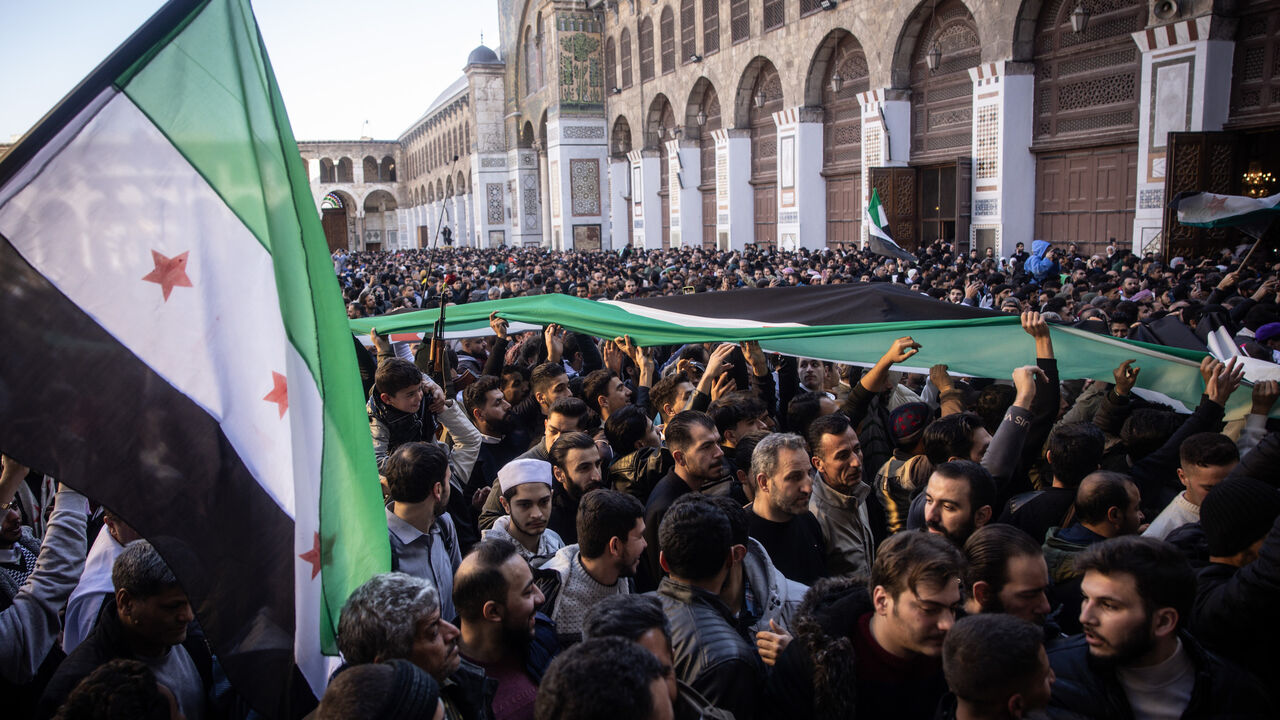 People chant slogans and wave flags in celebration after performing the first Friday prayer since the fall of the Assad regime at the Umayyad Mosque on Dec. 13, 2024 in Damascus, Syria.